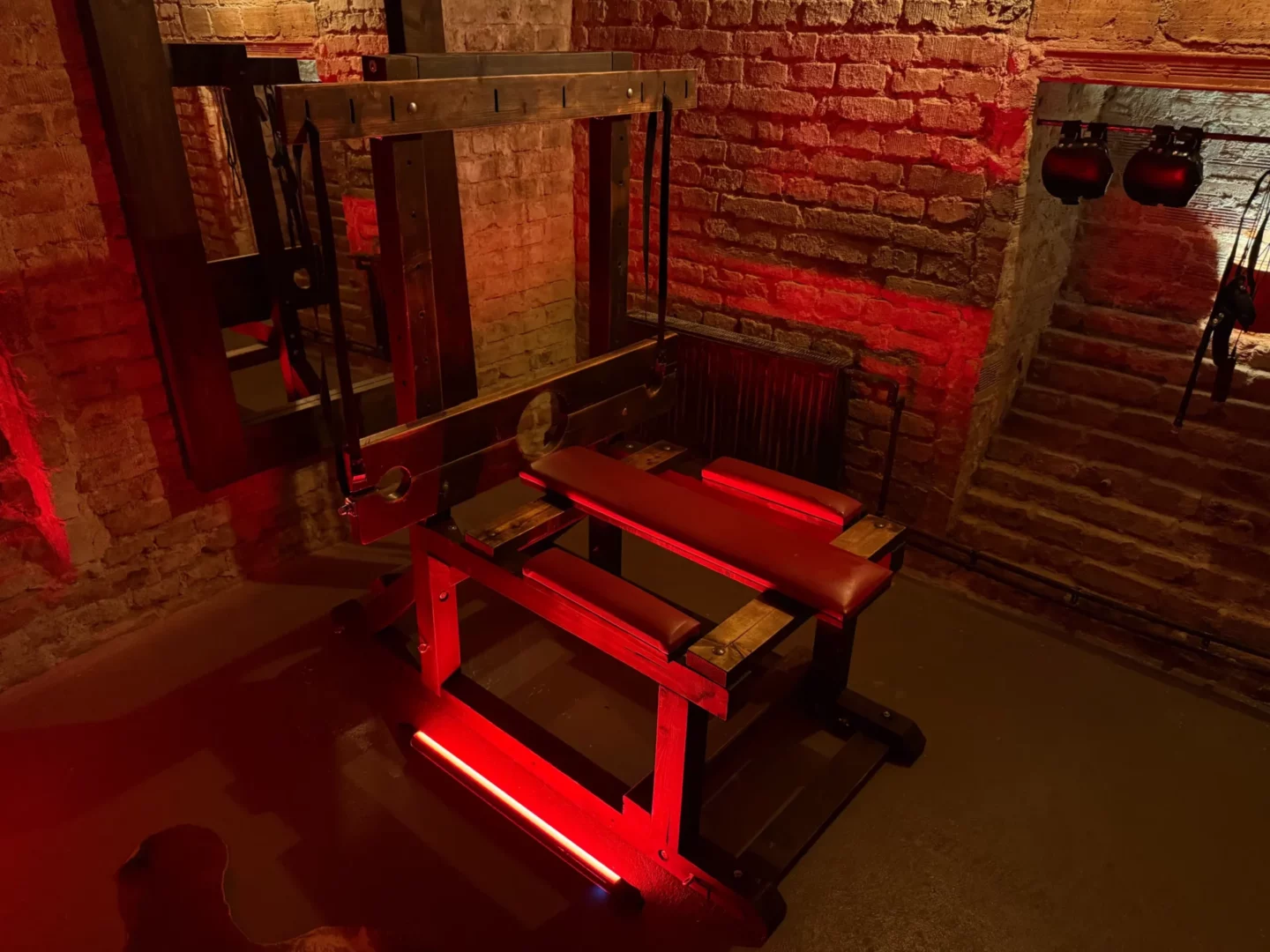 Dřevěná multifunkční lavice s kládou a červeným čalouněním, BDSM studio Vinohrady, Praha 2