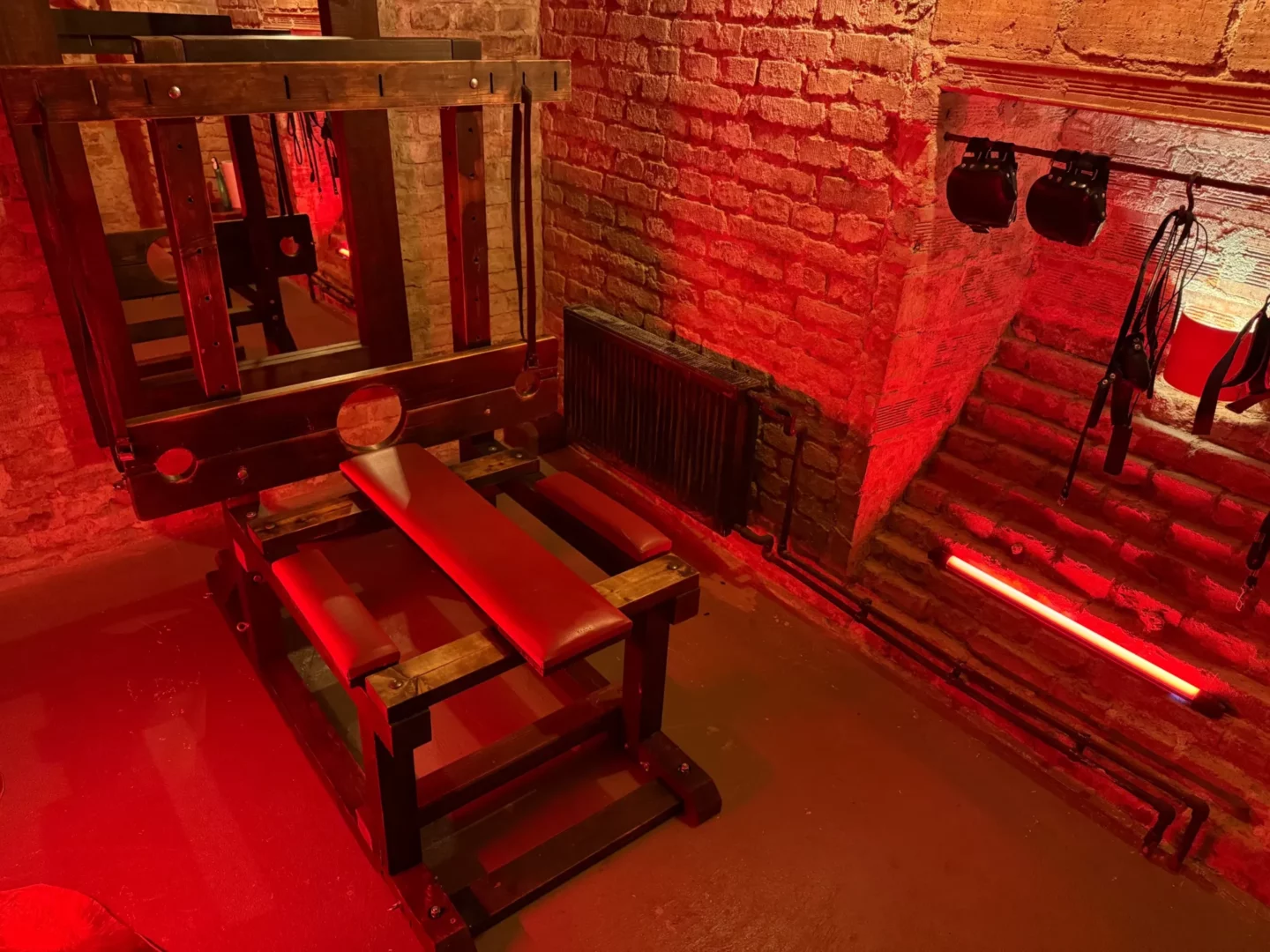 Multifunctional bench with a wooden log and restraints in a brick cellar, BDSM studio in Vinohrady, Prague 2