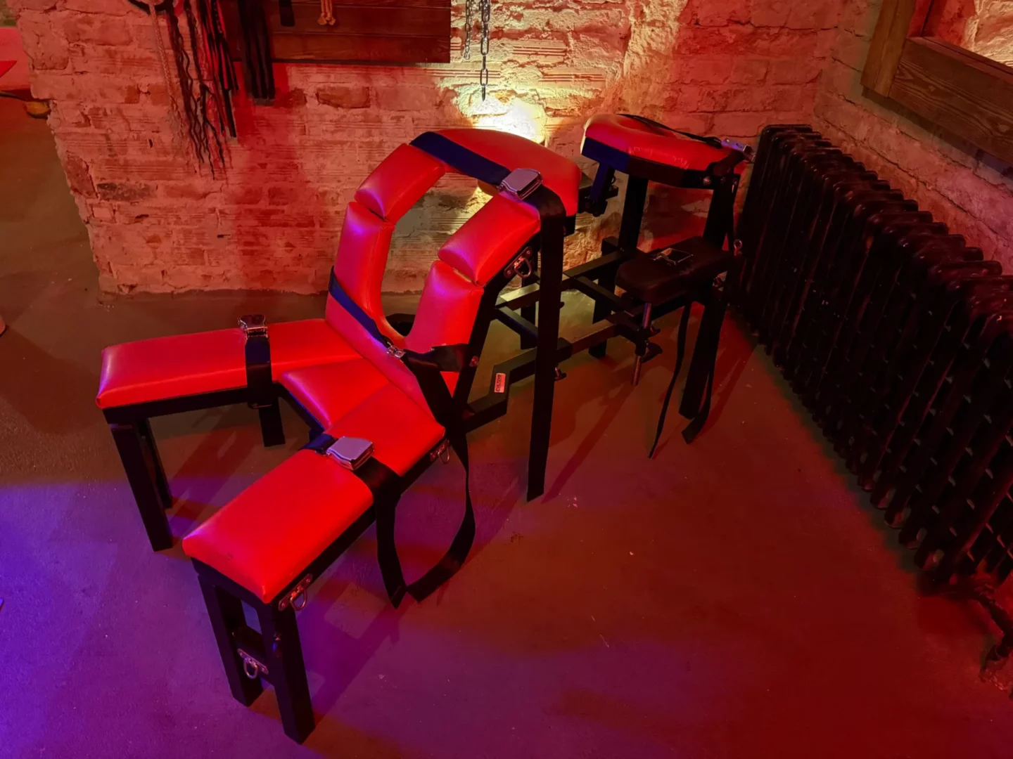 Červeně čalouněná poutací lavice s popruhy a přezkami, BDSM studio Vinohrady, Praha 2