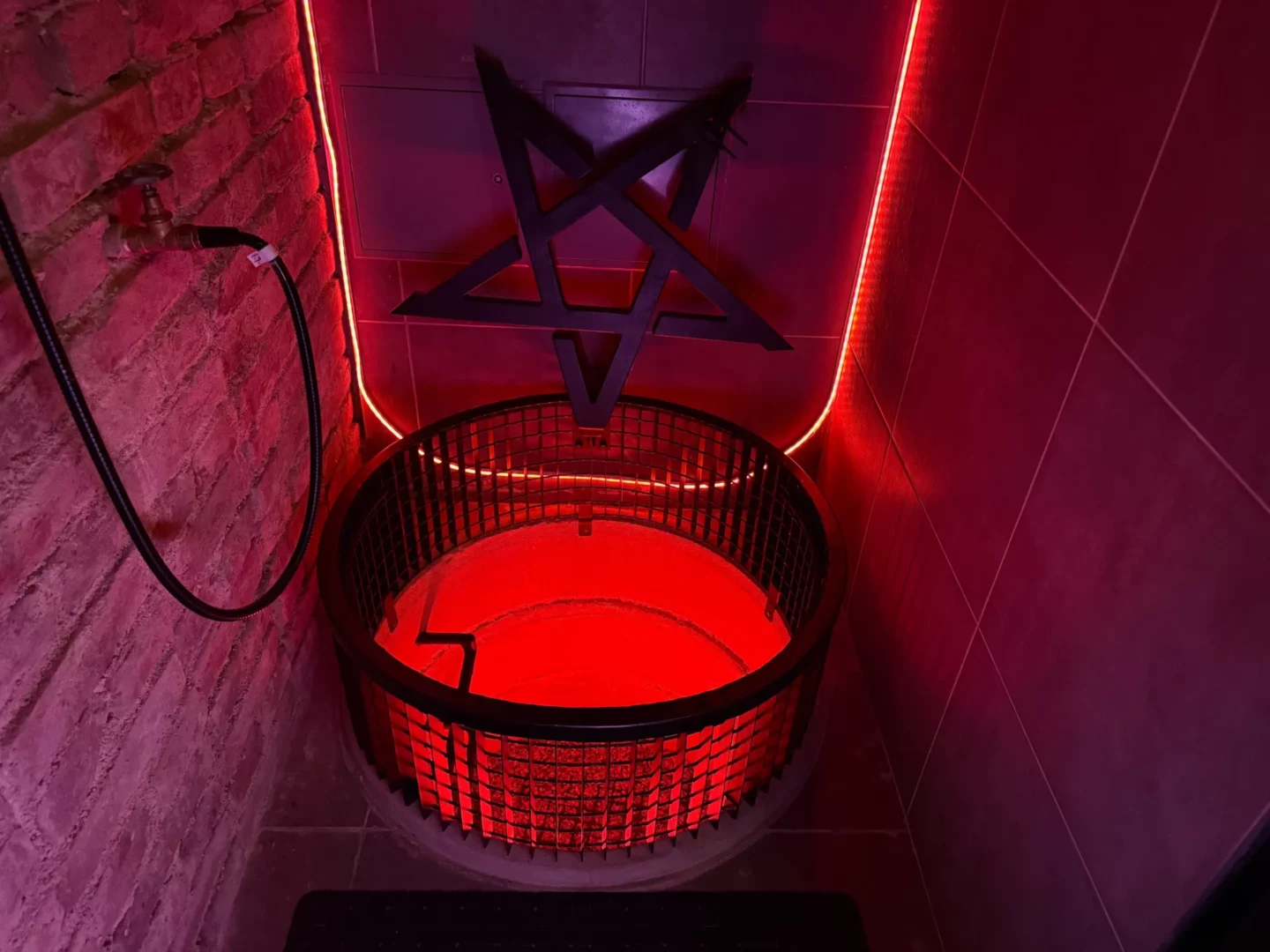 Ein runder, vergitterter Brunnen – ein Gefängnis im Boden mit einem Pentagramm darüber, BDSM-Studio Karlín, Prag 8