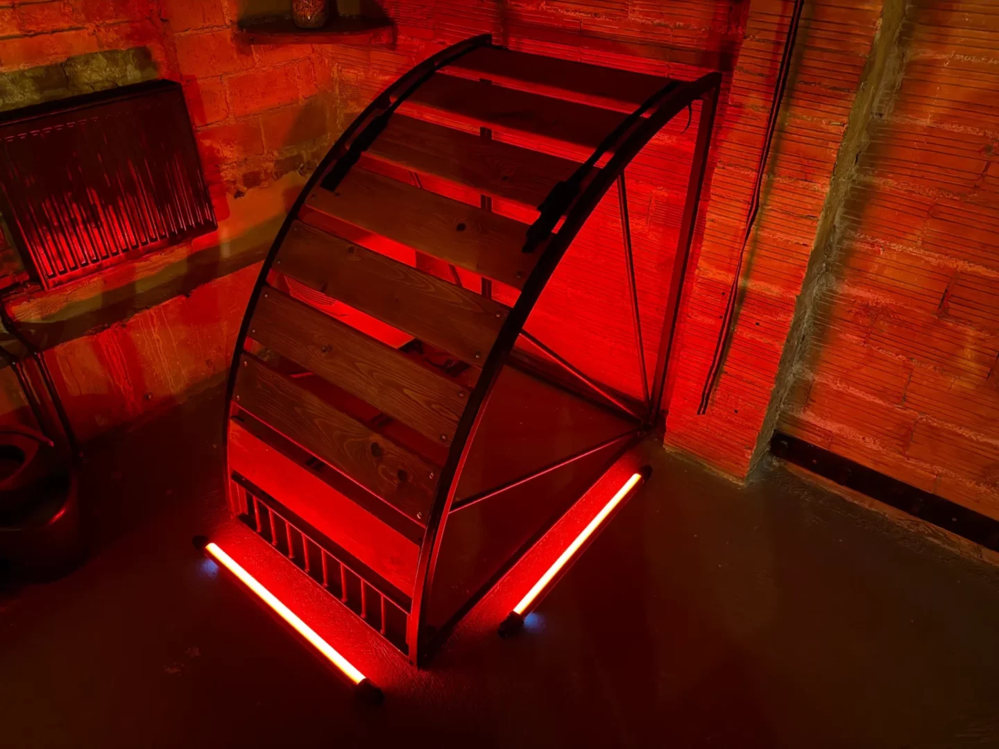Dřevěný výprask oblouk s červeným LED u cihlové zdi, BDSM studio Vinohrady, Praha 2